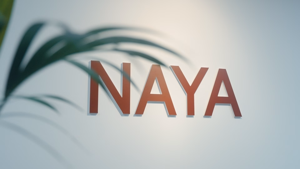 Billede af fire røde bogstaver på væggen hos Naya, som danner teksten NAYA
